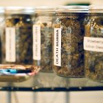 A rolling tray on a glass table with Cannabis in glass jars in the background